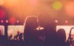 A couple in a healthy relationship kissing at a concert after going on a great date night.