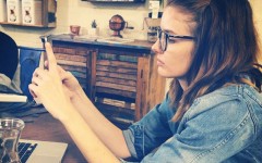 A girl having relationship problems at a coffee shop going through her boyfriend's text messages.