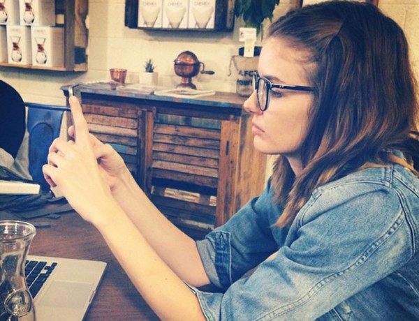 A girl having relationship problems at a coffee shop going through her boyfriend's text messages.