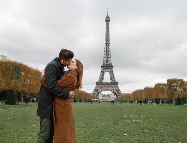 A couple in a healthy relationship kissing in front of the Eiffel Tower.