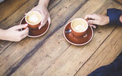 A couple's hands holding coffee cups while they are having a break up conversation.