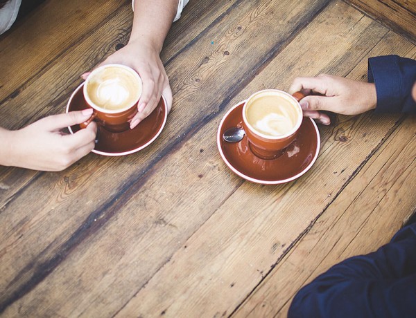 A couple's hands holding coffee cups while they are having a break up conversation.
