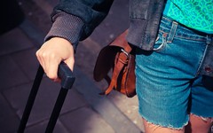 A woman who had relationship problems wheeling a suitcase because she's moving out after a break up.