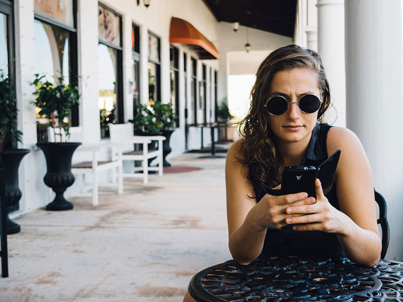 A girl having relationship problems looking mad at her phone.