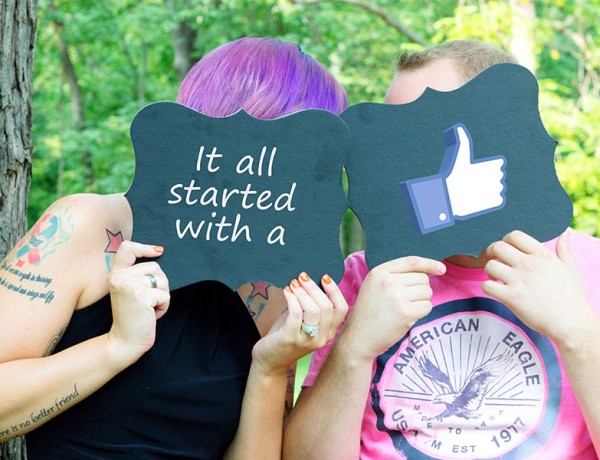 Two people at a wedding holding up signs saying it all started when they friended on Facebook.