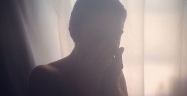 A woman upset in her room because she's going through a breakup.