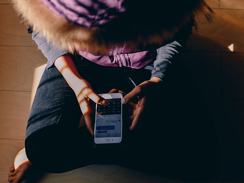 A girl texting while sitting down.