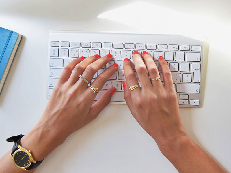 A woman with pink nail polish writing dating profile headlines for her online dating profile.