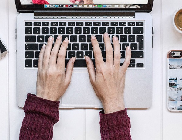 A woman typing on her computer who is online dating and trying to avoid online dating scams.