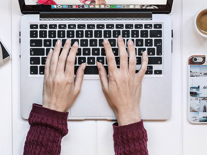 A woman typing on her computer who is online dating and trying to avoid online dating scams.