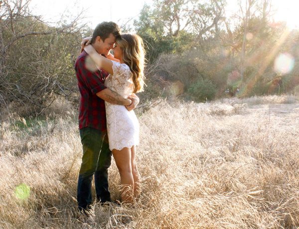 A couple hugging in a field.