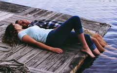 A couple having the relationship talk while laying on a dock with their feet in the water.