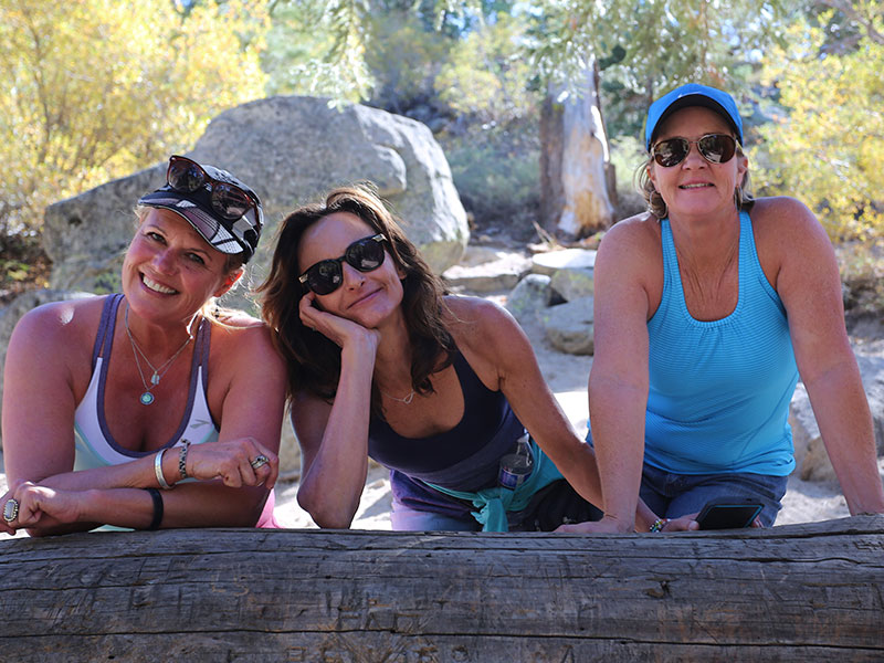 A group of happy women over 50 smiling while taking a break on a hike.