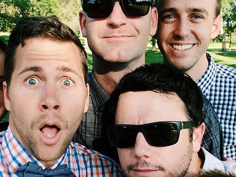 A group of men in their 30s smiling and joking together.