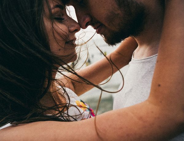 A woman wondering how to know if he's the one while hugging a man on the beach.