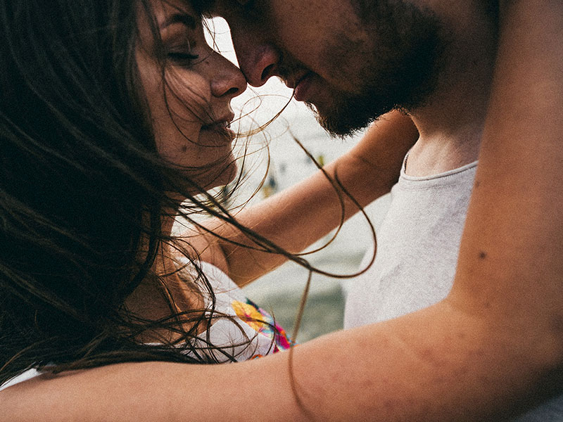A woman wondering how to know if he's the one while hugging a man on the beach.
