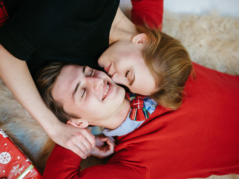 A loving couple cuddling on a blanket during the holidays.
