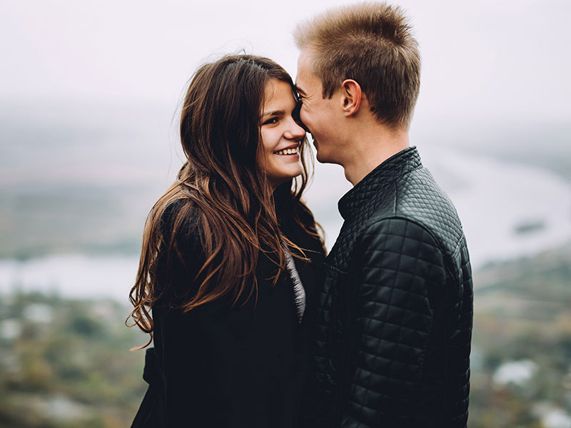 A women and a man on a first date cuddling on the beach.