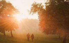 An unlikely couple walking into the sunset in a field.