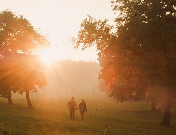 An unlikely couple walking into the sunset in a field.