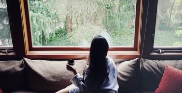 A woman who's getting over a divorce looking out her window drinking tea.
