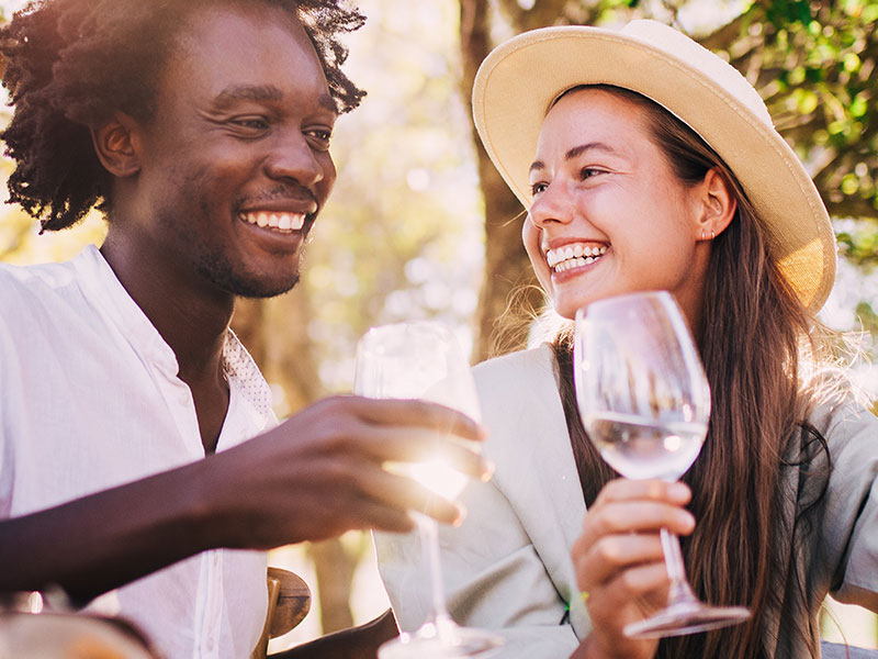 A couple laughing at an outdoor restaurant after taking these dating tips from a chef.