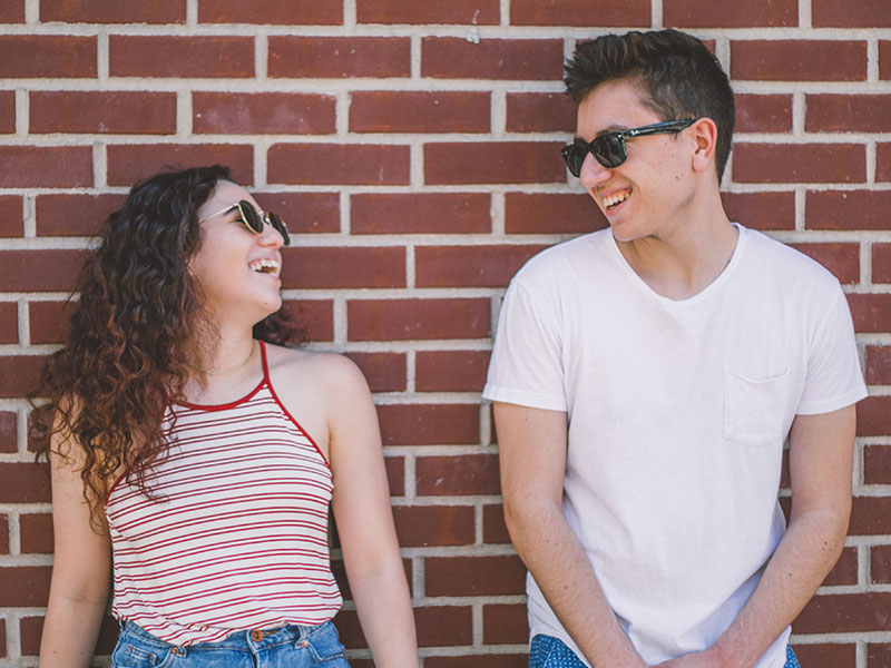 Two people looking at each other and smiling because this man figured out how to tell if a girl likes you.