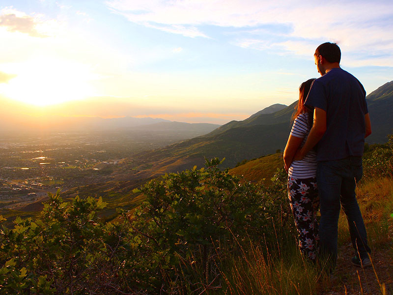 A man and woman who's dating someone who's newly divorces on a cliff looking at the sunset.