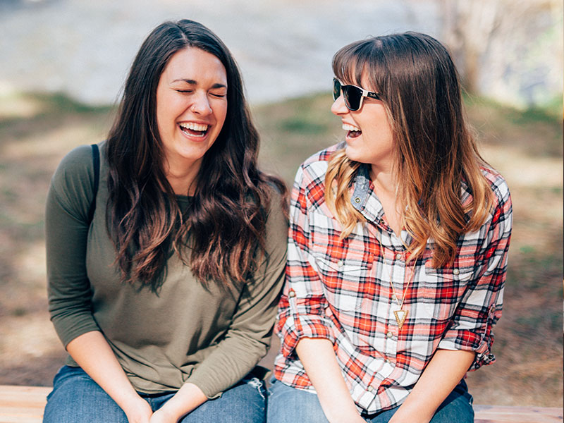 Two women discussing dating tips for women in their 20s and 30s while laughing together.