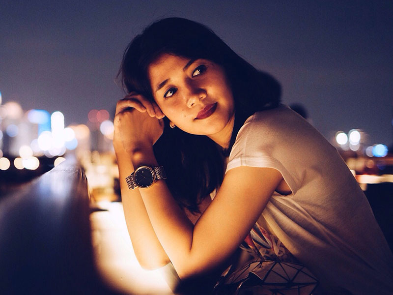 A woman sitting on a balcony wondering how to break up with someone in a nice way.