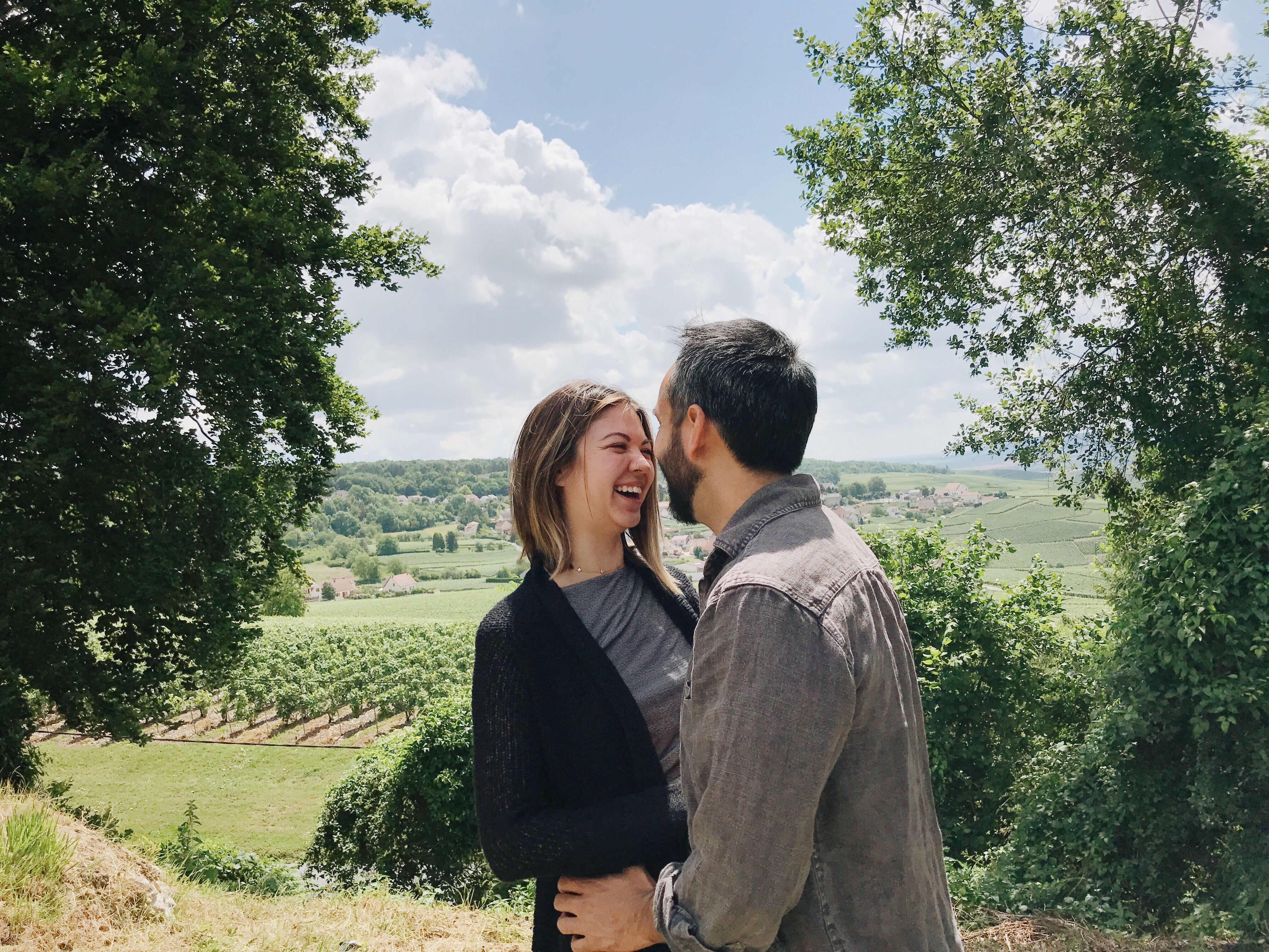 A woman who's dating again at 40 laughing with a man on a hill while wine tasting.