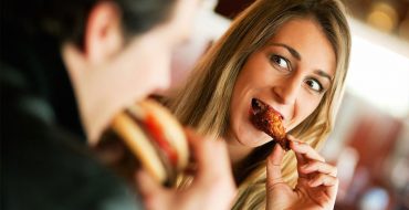 A woman eating a chicken wing after reading this ultimate guide to food and dating.