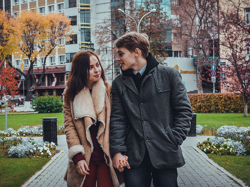 A couple holding hands in the park on their way to Thanksgiving dinner with the family.