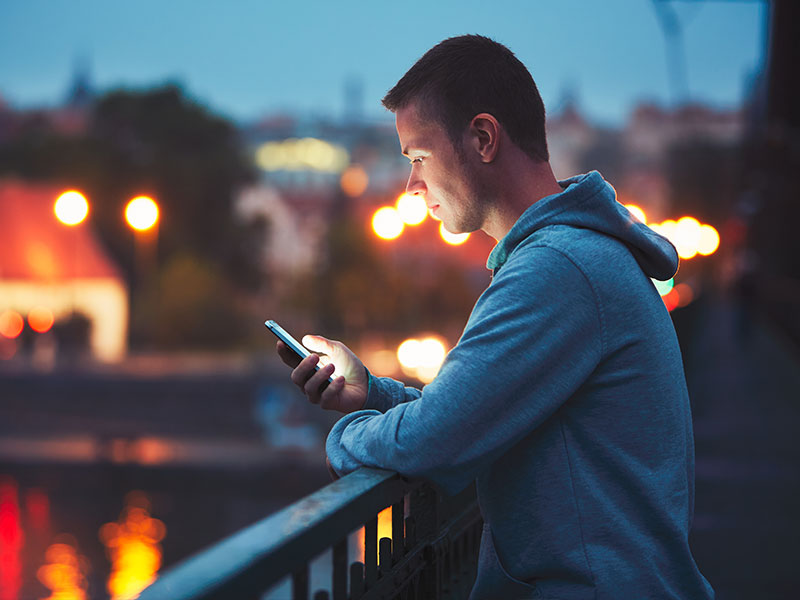 A man on his phone reading pof headlines for women and trying to pick someone to talk to.