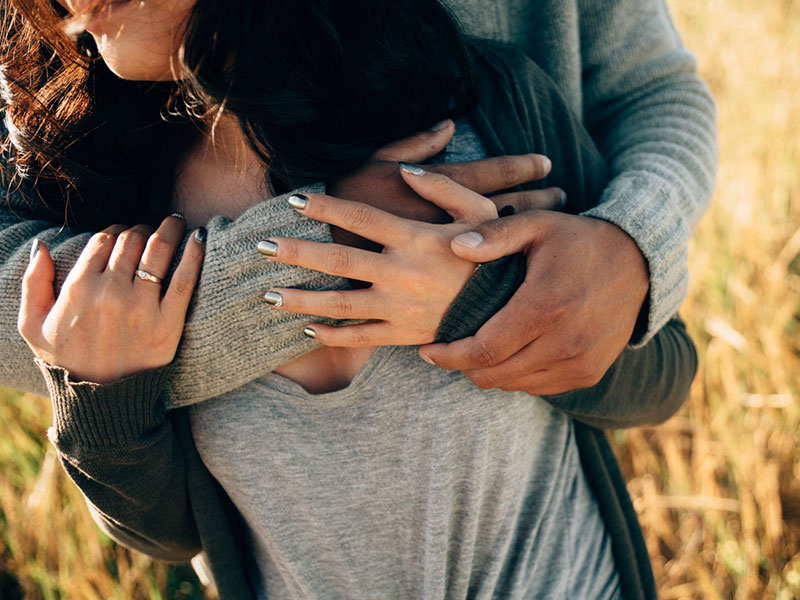 A woman dating a widower hugging him in a field.