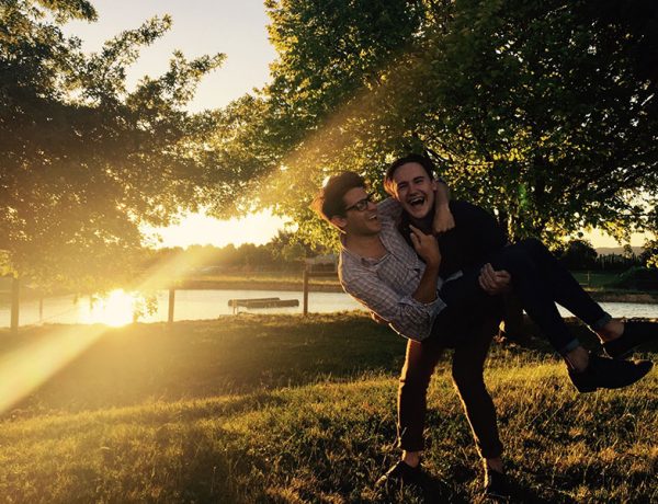 Two guys who listened to these dating tips laughing in a field together.