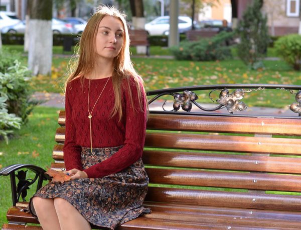 A woman who's still single, sitting on a park bench alone.