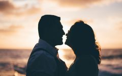 Two people who are senior dating looking into each other's eyes at sunset on a beach.