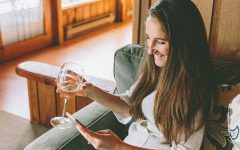 A woman who was wondering how to talk to guys online typing on her phone while drinking wine.