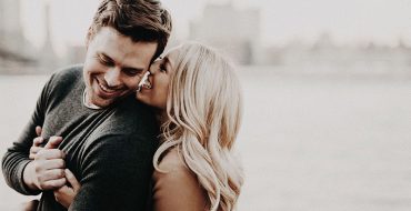 Two people who are in love displaying infatuation symptoms as they huge in front of a cityscape.