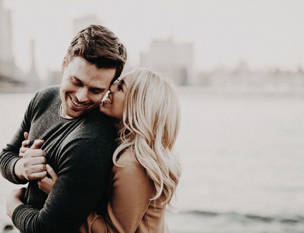 Two people who are in love displaying infatuation symptoms as they huge in front of a cityscape.