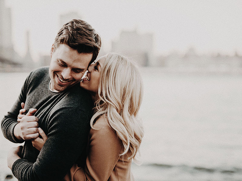 Two people who are in love displaying infatuation symptoms as they huge in front of a cityscape.