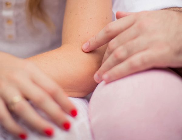 A woman who listened to these subtle flirting tips sitting next to a man touching his leg.