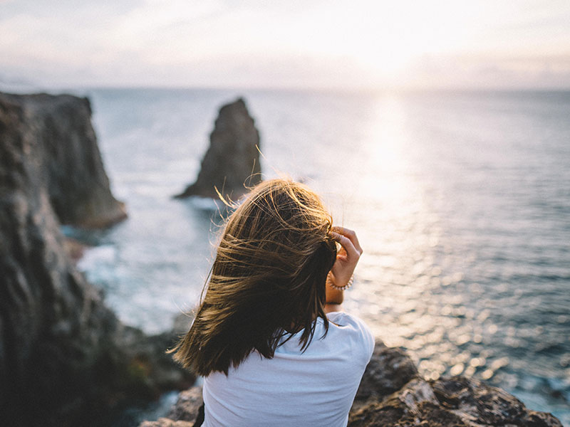 A woman looking off the edge of a cliff wondering if it's time for her long term relationship break up.