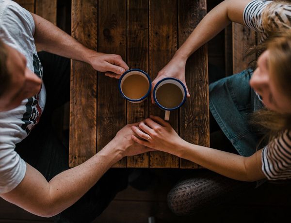 Two singles over 40 holding hands while on a date at a coffee shop.