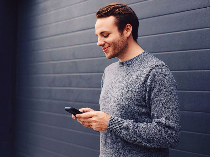 A man who read these online dating tips for women looking at his phone and smiling.