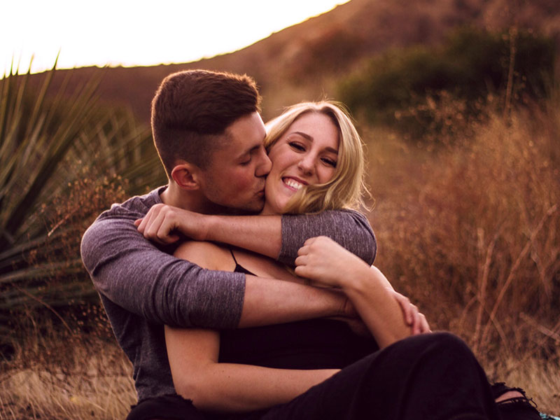 A woman who took these best first date tips for women being hugged by a man on a hill.