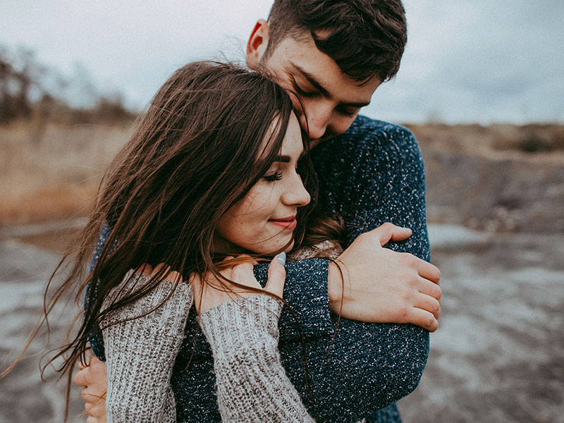 A woman who took these tips on how to ask a man out hugging her date on the beach.