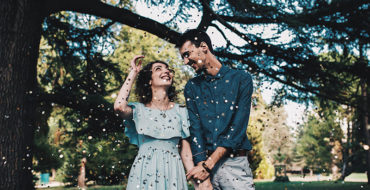 A woman who learned how men fall in love, smiling with her husband under a tree at their wedding.
