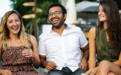 A guy laughing with his girlfriend and her friends who he's meeting for the first time.